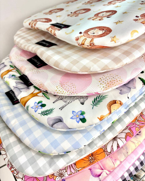 Stack of colourful baby pram and bassinet liners with various patterns and designs.