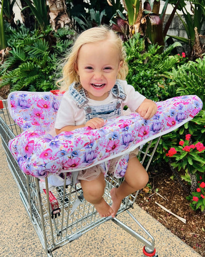 Happy baby girl sitting in a trolley with the Whimsy Floral Harmony J trolley liner, looking comfy and cheerful