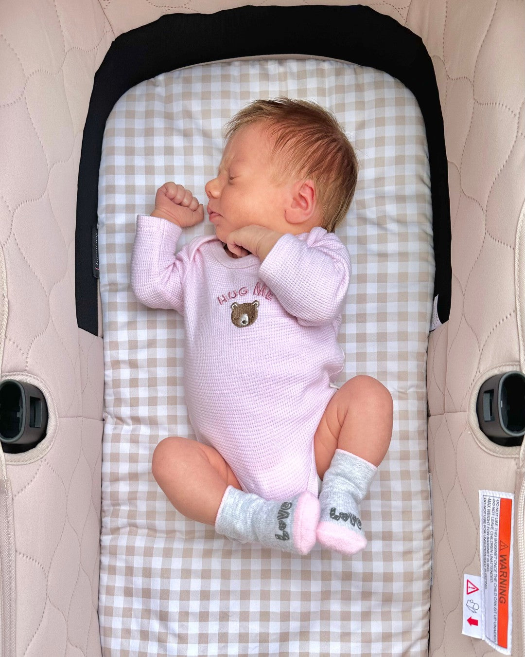 Baby girl lying in her Bugaboo Kangaroo bassinet with a Gingham Beige custom bassinet liner, soft and cosy.