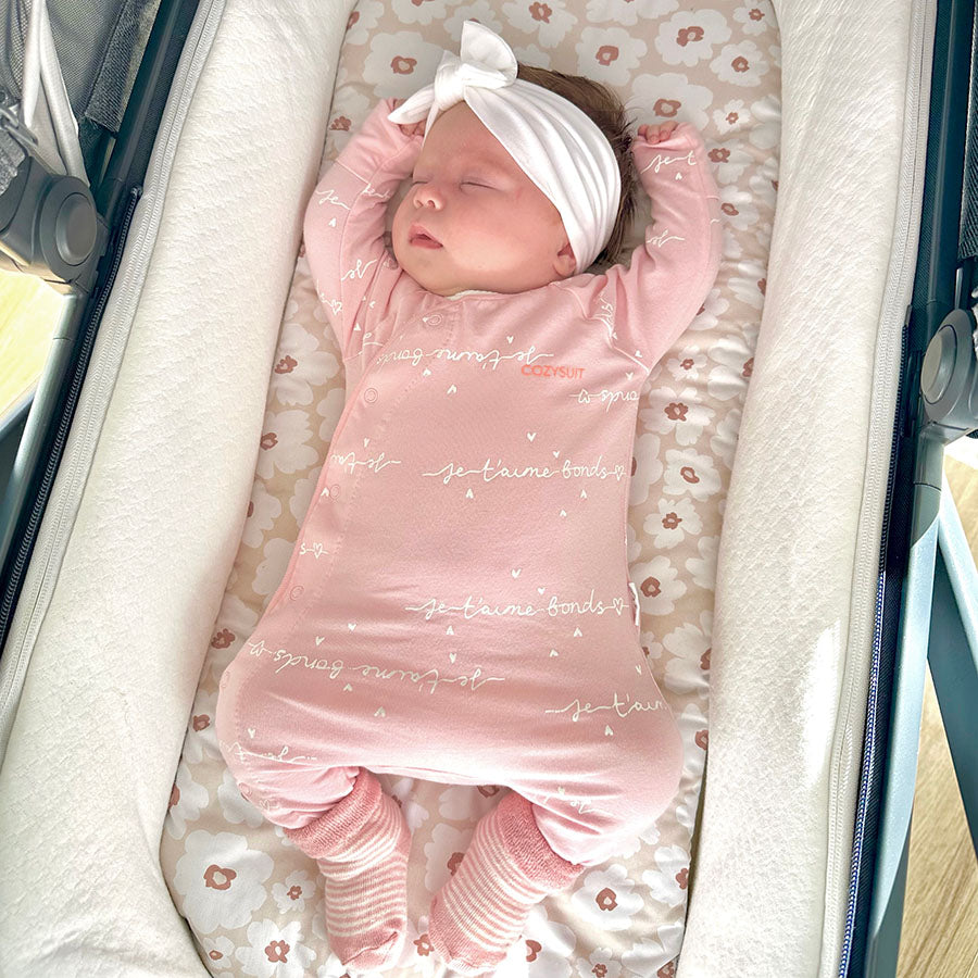 Baby sleeping on a floral Harmony J bassinet liner in an Uppababy pram.