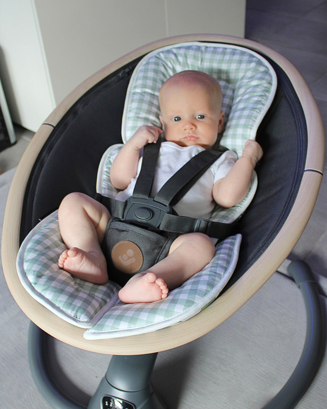 Baby boy with his newborn insert, looking comfortable in the baby swing.